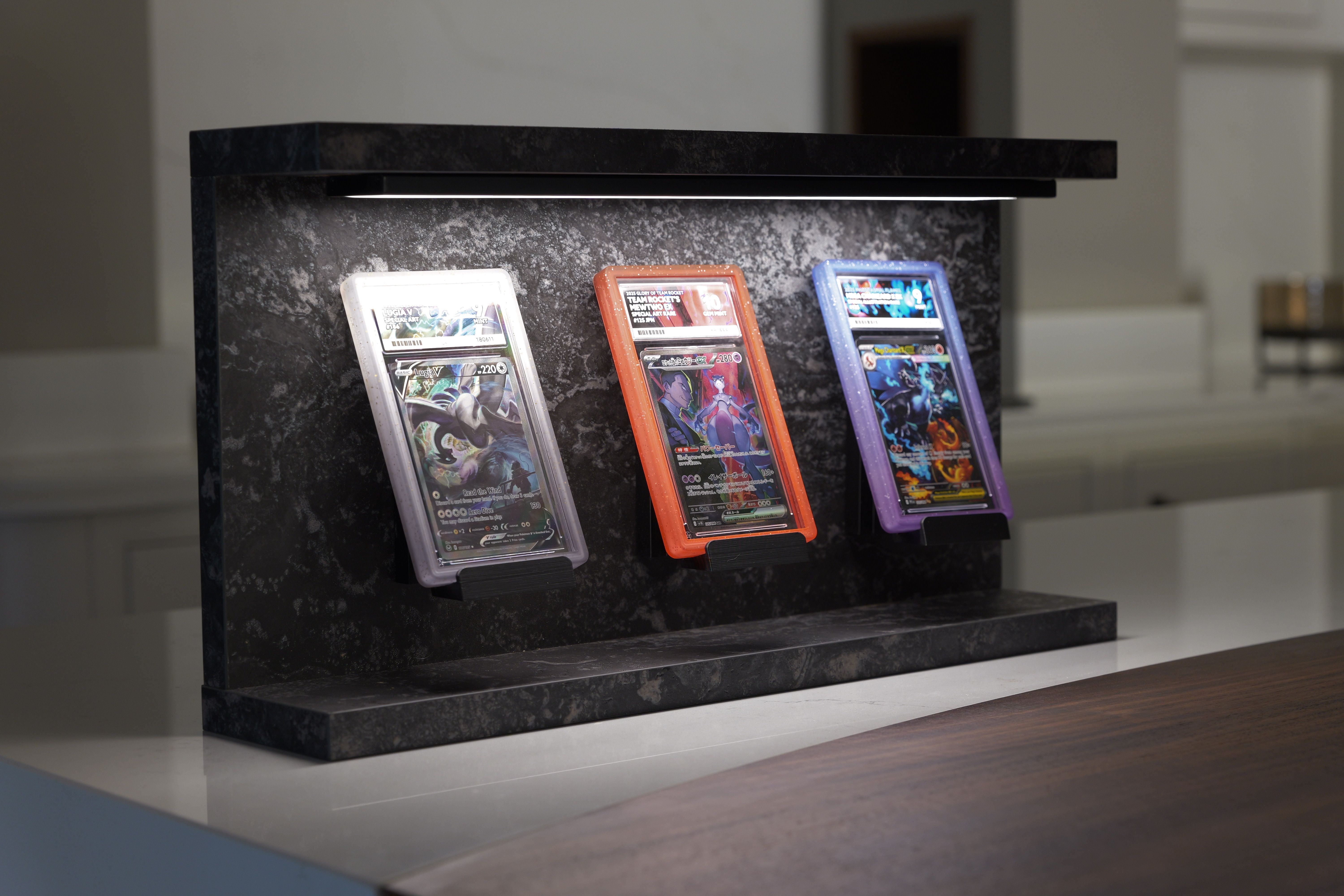 Slab Stand Obsidian graded card display stand with three PSA slabs under LED light